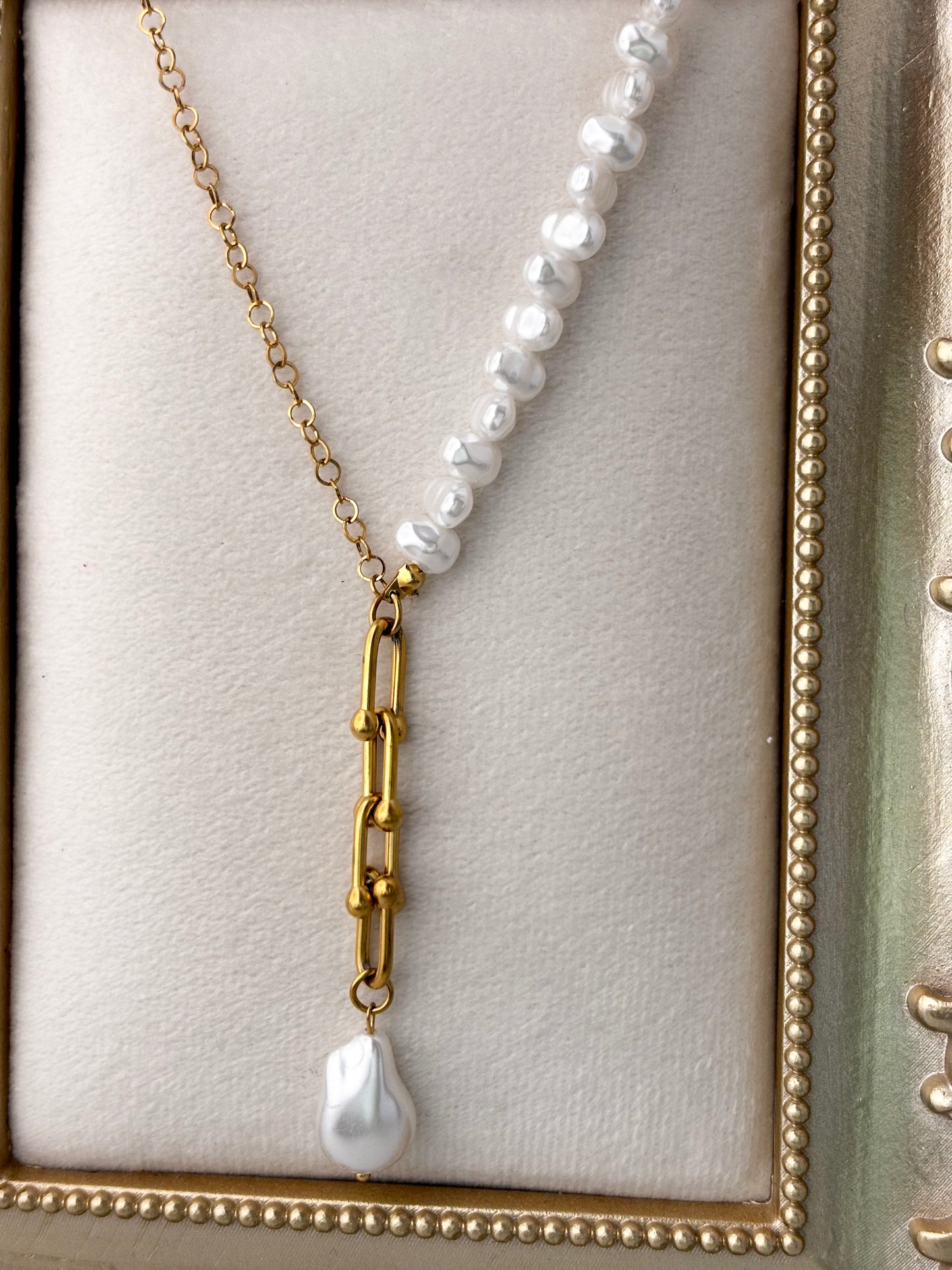 Pearl necklace with a gold chain and pendant on a light background