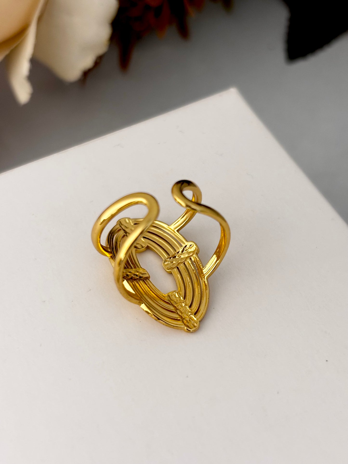 Gold ring with intricate design on a white surface